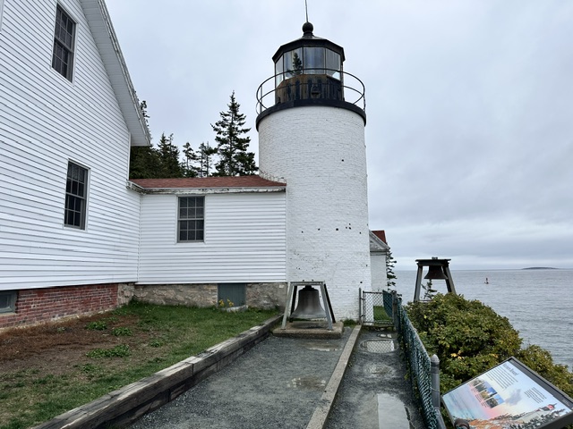 A close view of a white lighthouse tower beside its attached building