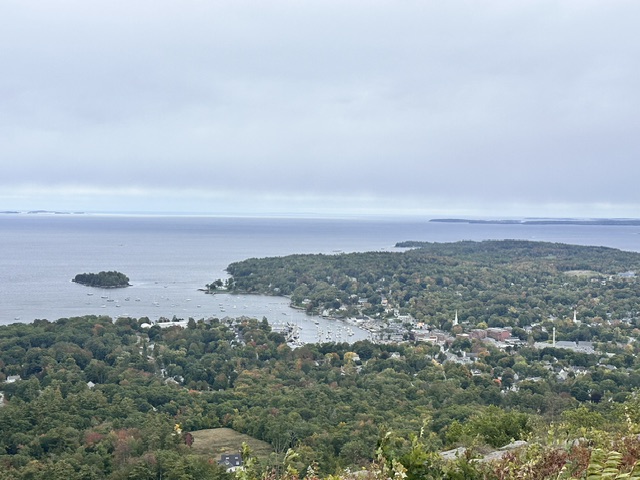 An elevated overlook view of Camden Harbor, the surrounding coastline, and foliage
