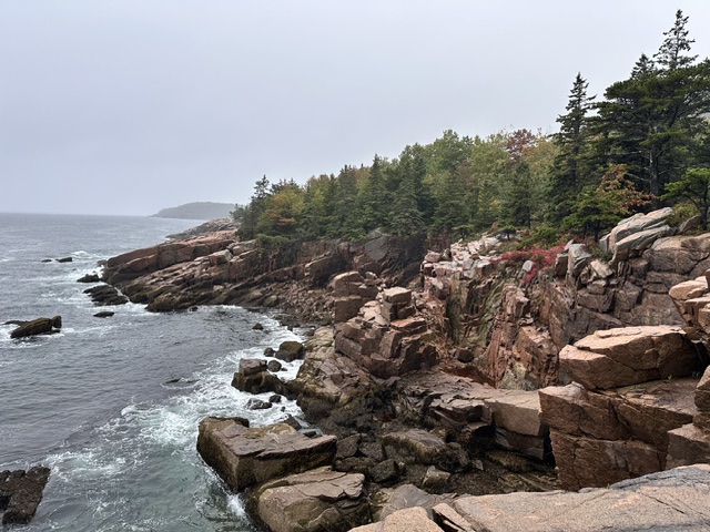 A rocky Atlantic shoreline with waves and autumn trees